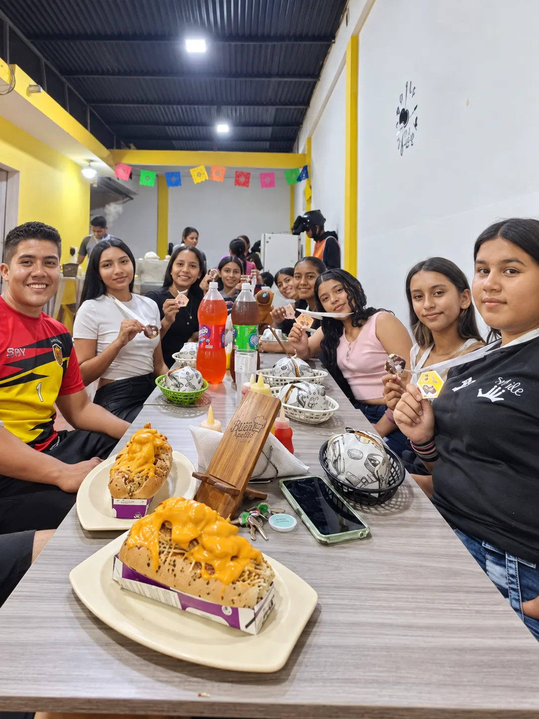 Grupo de jóvenes con perros calientes gratinados en una mesa de Flakko Burguer